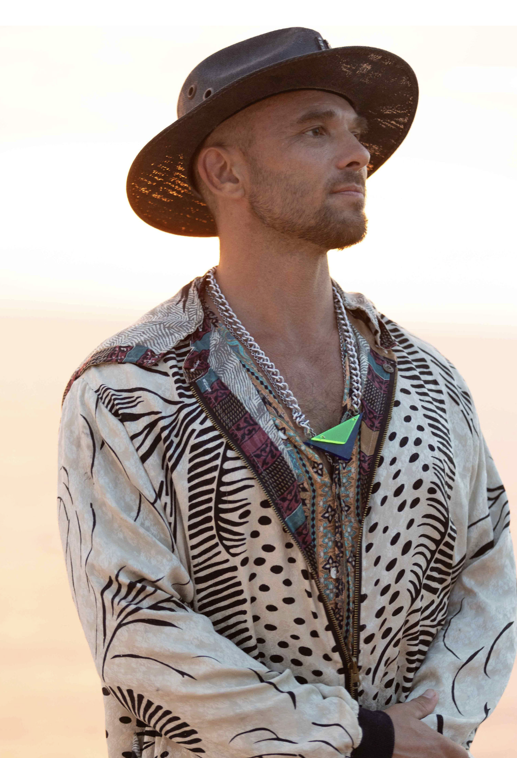 Spooky wearing a patterned shirt and black hat, looking toward the horizon in warm evening light